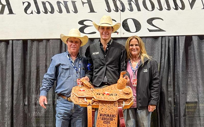 Slade Wood (center) accepts a custom champion saddle during the CNFR with coach Joey Almand (right) and his wife Sugar Almand.